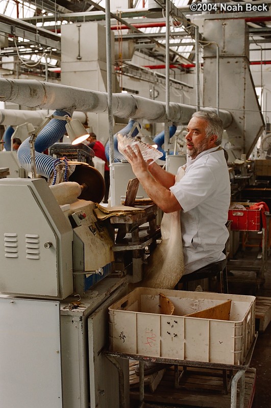 July 6, 2004: This craftsman is grinding a pattern into a piece of crystal with a grinding wheel. The pattern is drawn onto the piece with a marker.