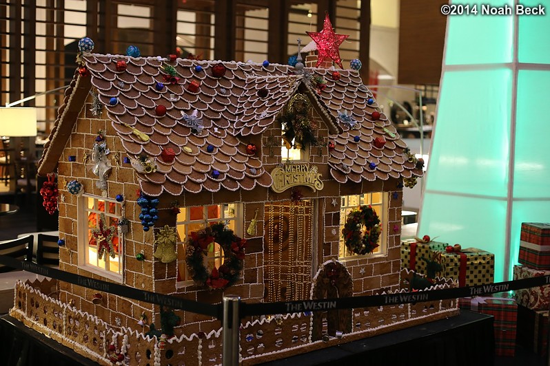 December 7, 2014: Gingerbread house (made of actual gingerbread) in the Westin atrium.  The &quot;The Westin&quot; barrier tape is about waist high, so this structure is taller than I am.